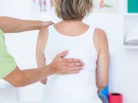Un paciente con quejas de dolor de espalda en la zona de los omóplatos siendo examinado por un médico. 